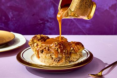 Banana bread pudding on a plate with caramel being poured from a decorative pitcher
