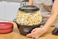 A person lifts up the West Bend Stir Crazy Electric Hot Oil Popcorn Popper