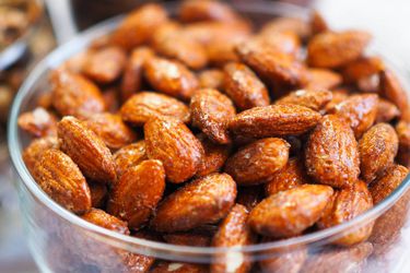 Closeup of smoky candied almonds in a glass bowl.