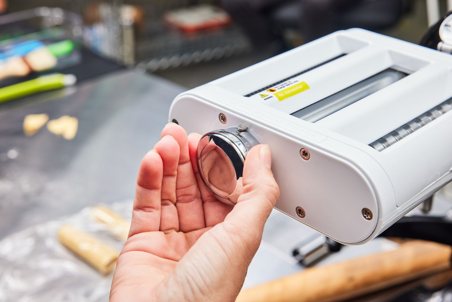 A person adjusts the Antree Pasta Maker Attachment 3 in 1 Set for KitchenAid Stand Mixers