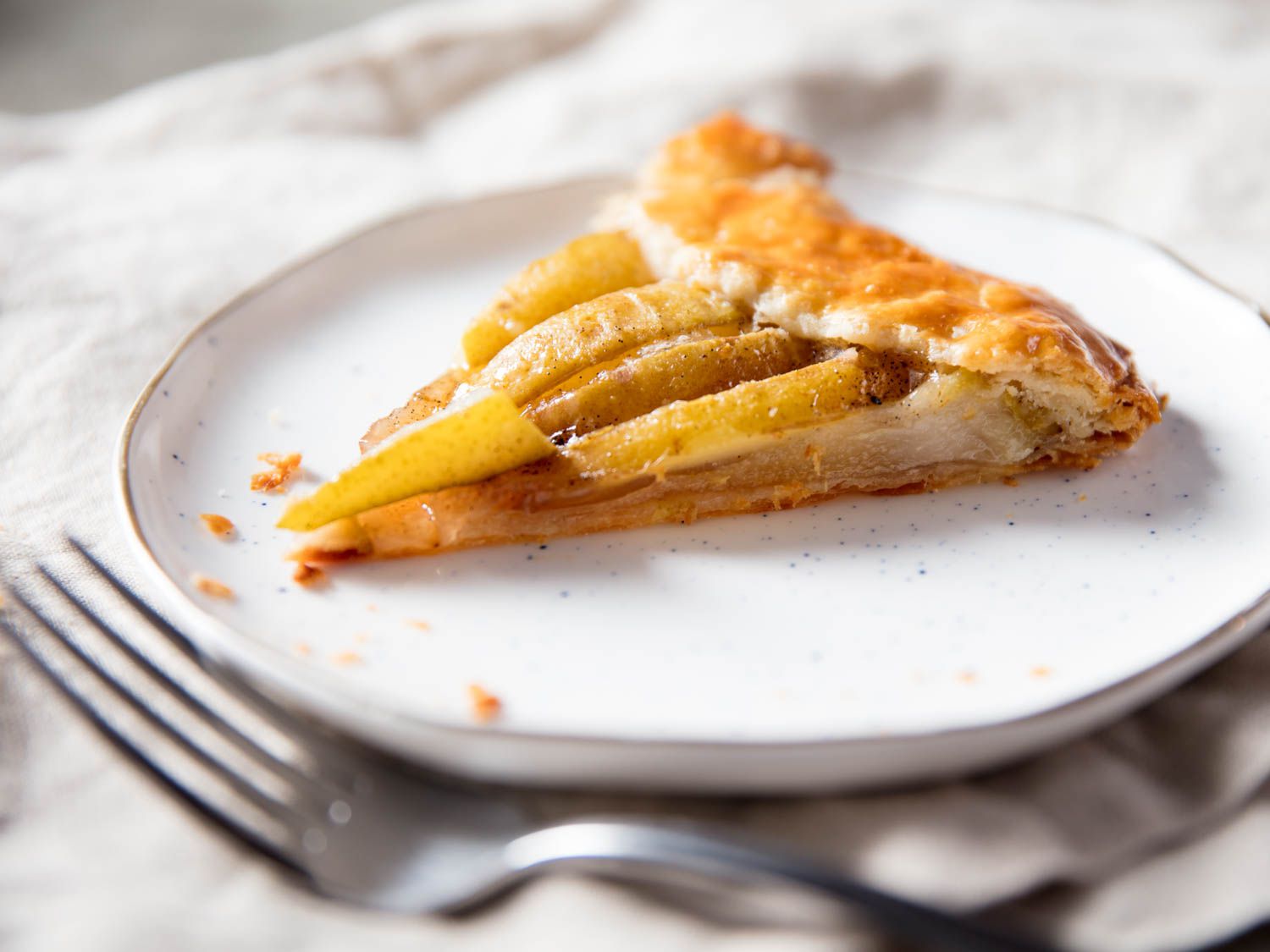 A slice of pear galette, shot from an angle to show off its thin profile.