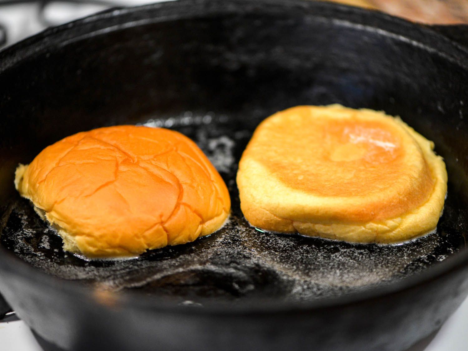 Toasting potato bun halves in buttered skillet.