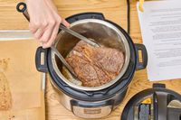 A person cooks meat in the Instant Pot Pro 10-in-1 6-Quart Pressure Cooker