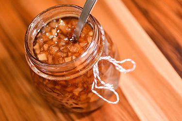 Open jar of pear and ginger preserves with a spoon in it