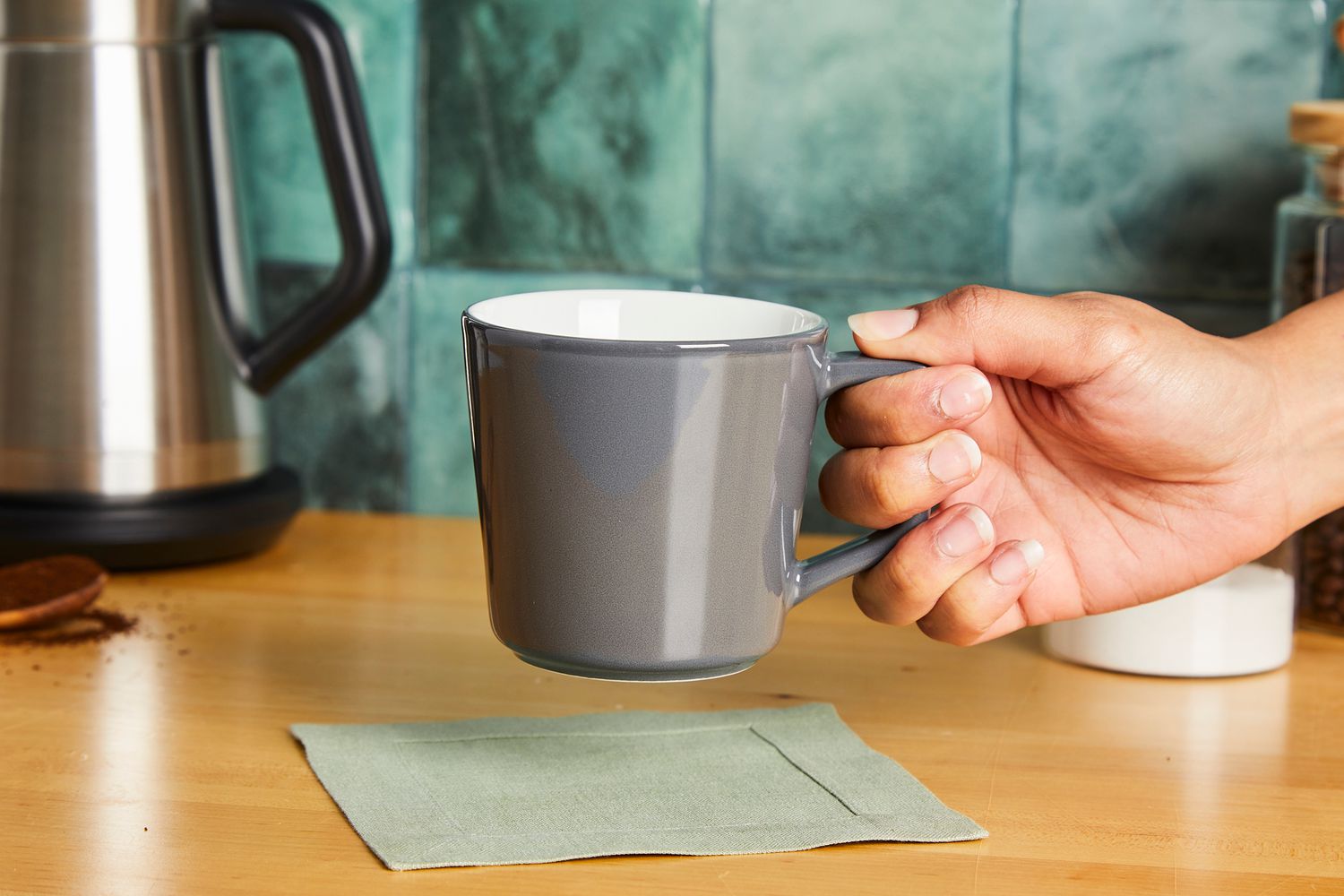 A person holding a grey coffee cup.