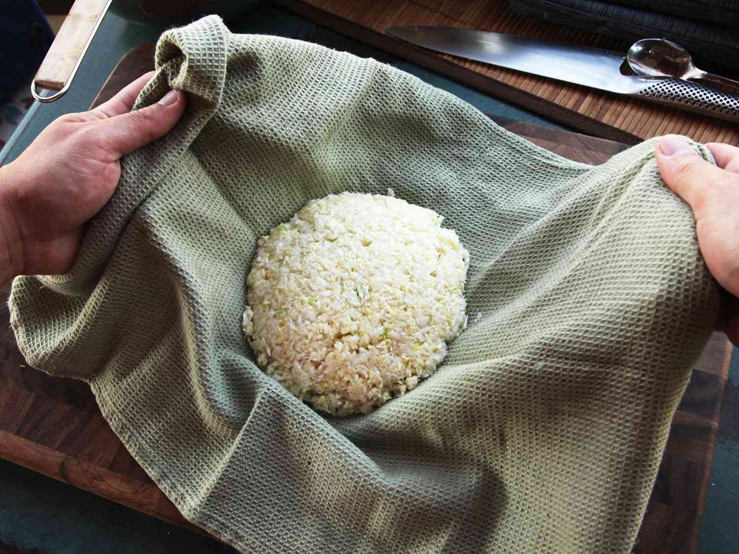 Placing a mound of salted, finely minced napa cabbage in a kitchen towel.