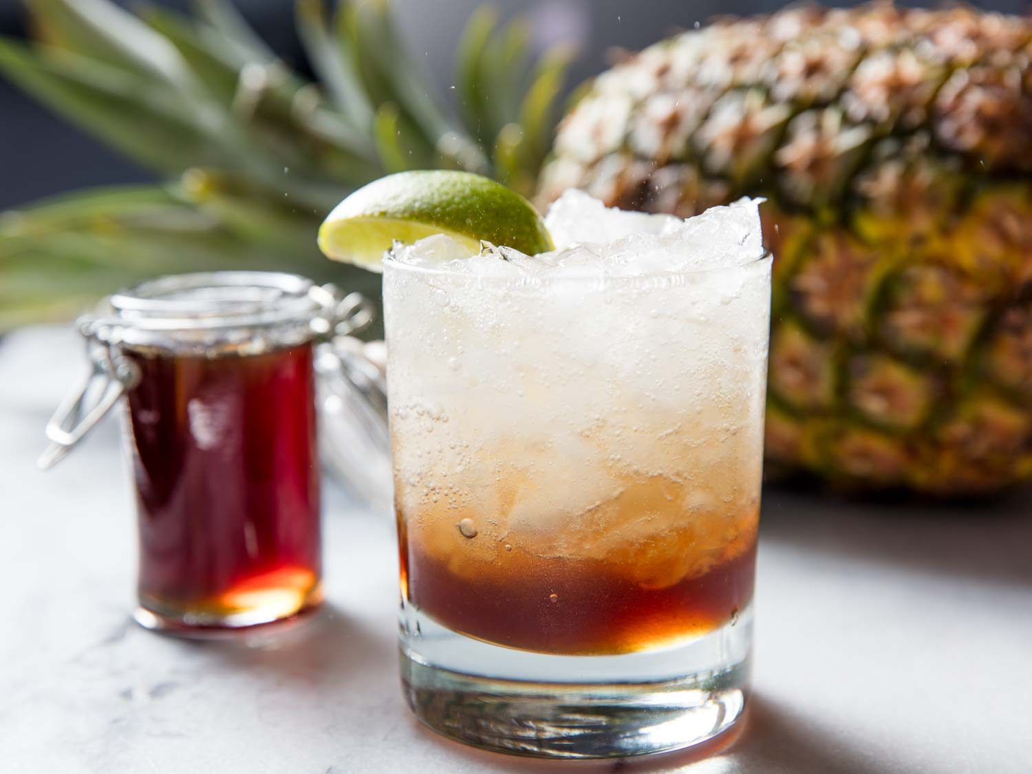 A fizzy glass of pineapple soda with rum and lime.