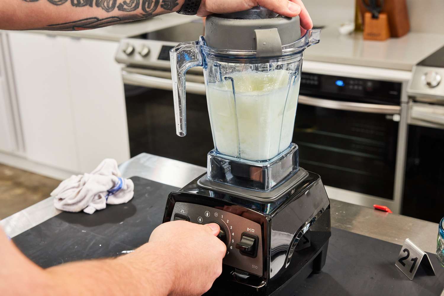 A person using a Vitamix blender to blend a smoothie.