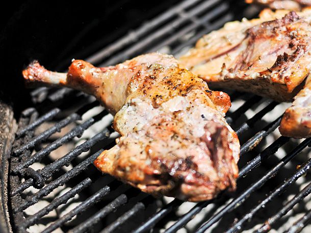 A chicken leg quarter is turned skin-side down on the grill.