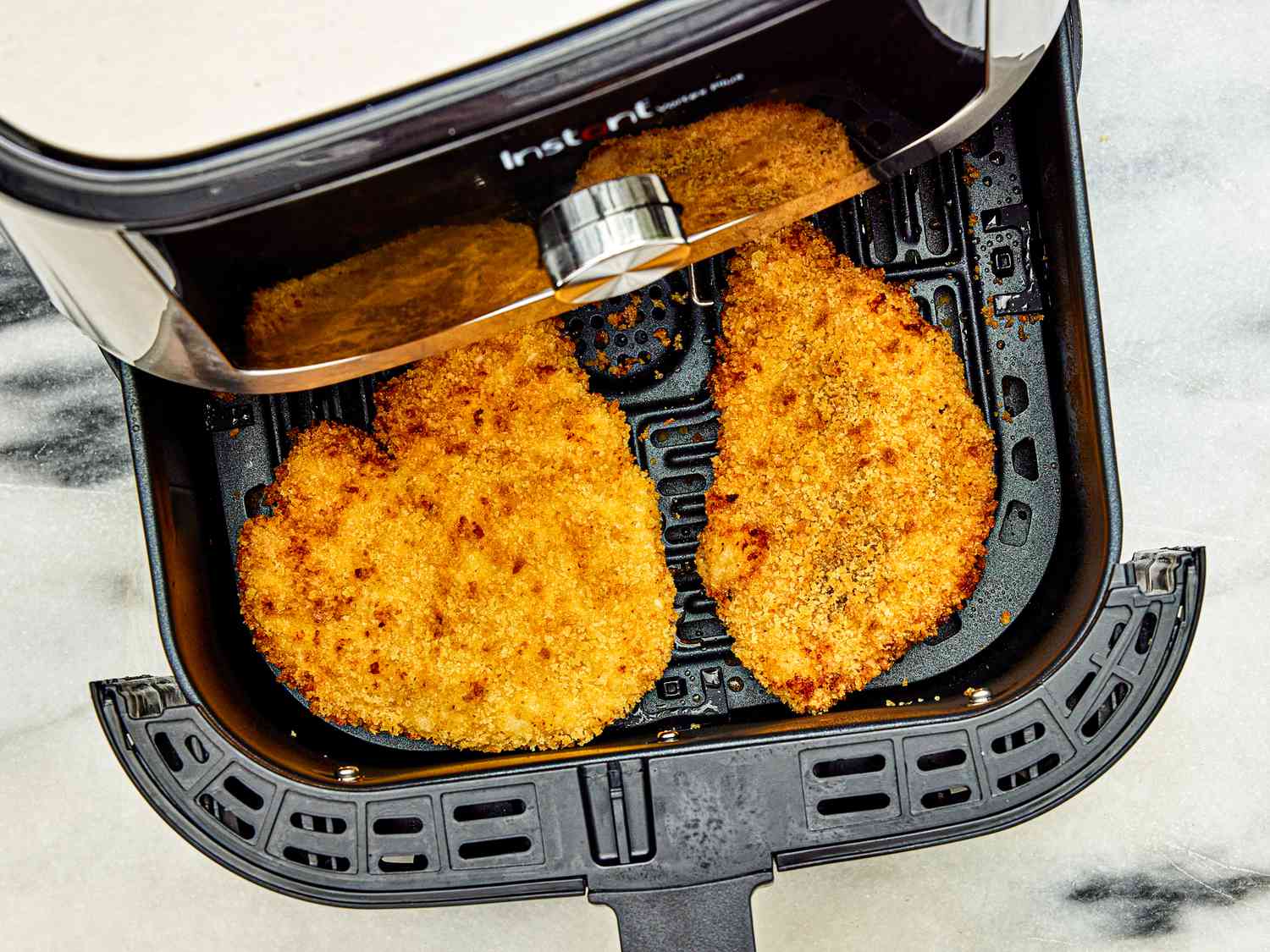 An air fryer is opened to reveal chicken katsu, finished and ready to serve.