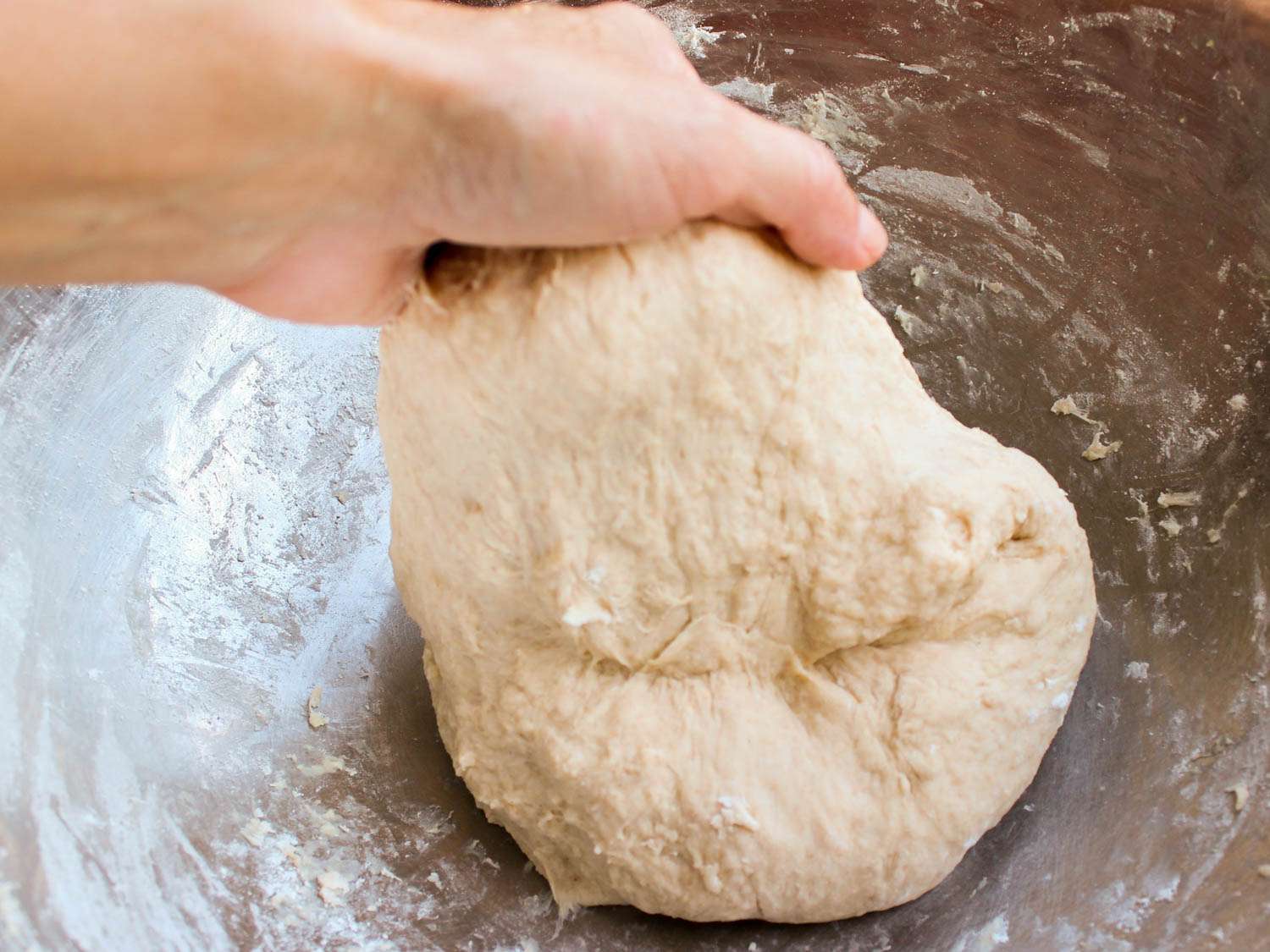 Kneading pita dough in a bowl.