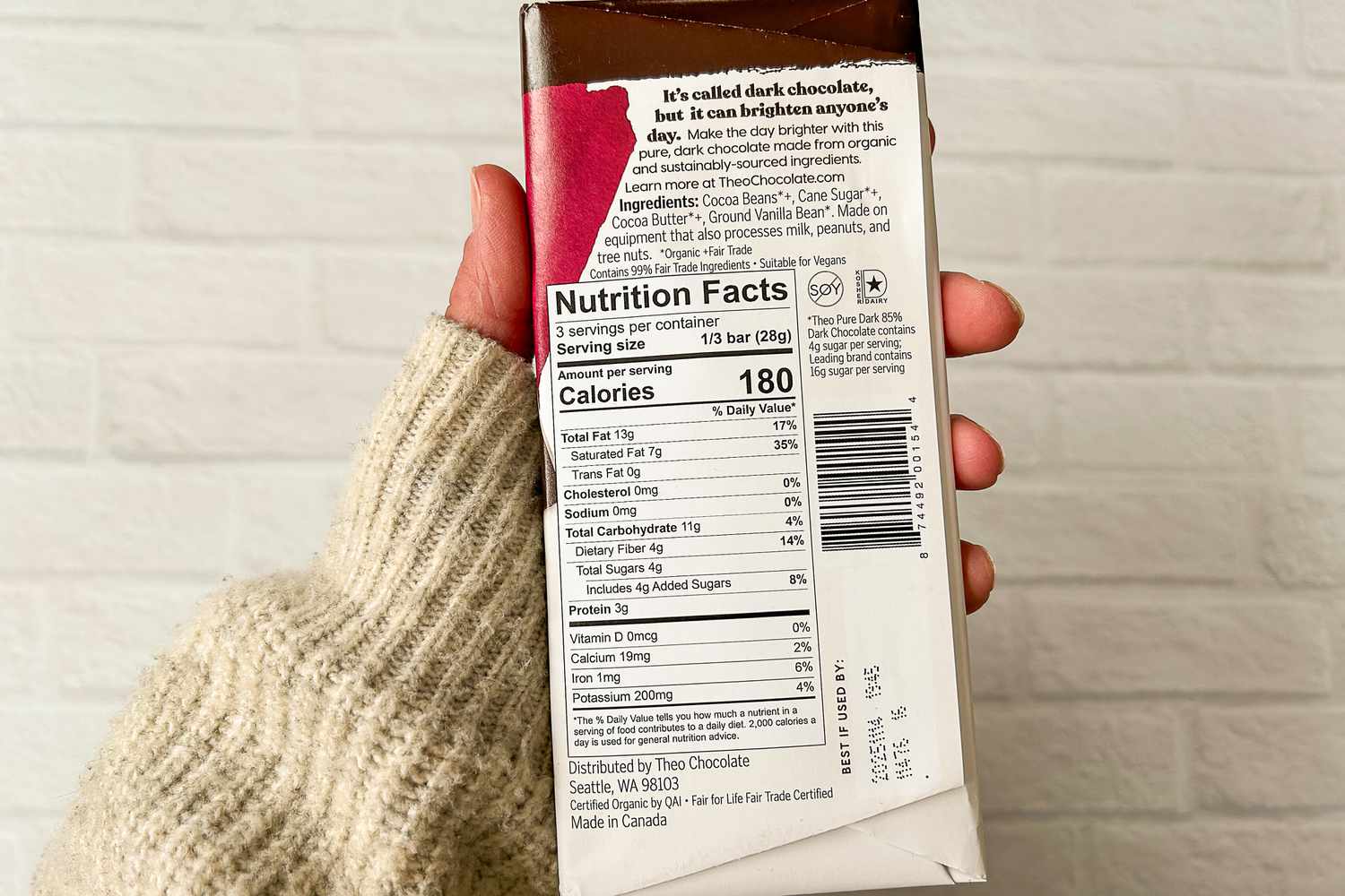 A person holding Theo Pure Dark 85% Chocolate Bar showing the nutrition facts