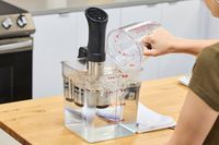 Person pouring water into a Anova Culinary Precision Cooker 3.0 on a countertop