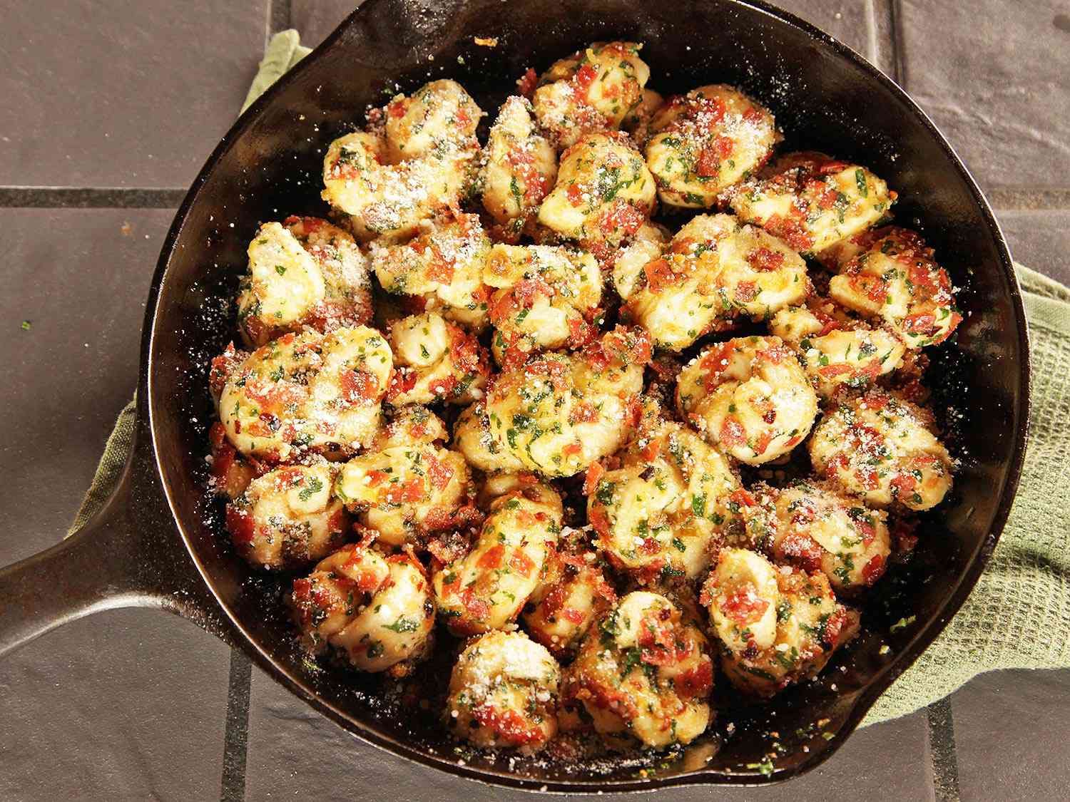 A cast iron pan of pepperoni garlic knots proofing before baking