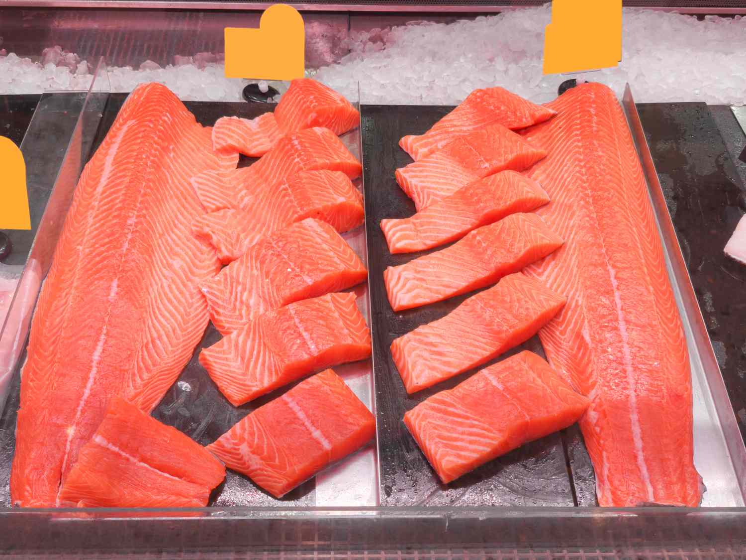 Slices and fillets of salmon arranged on display in a storefront or market counter