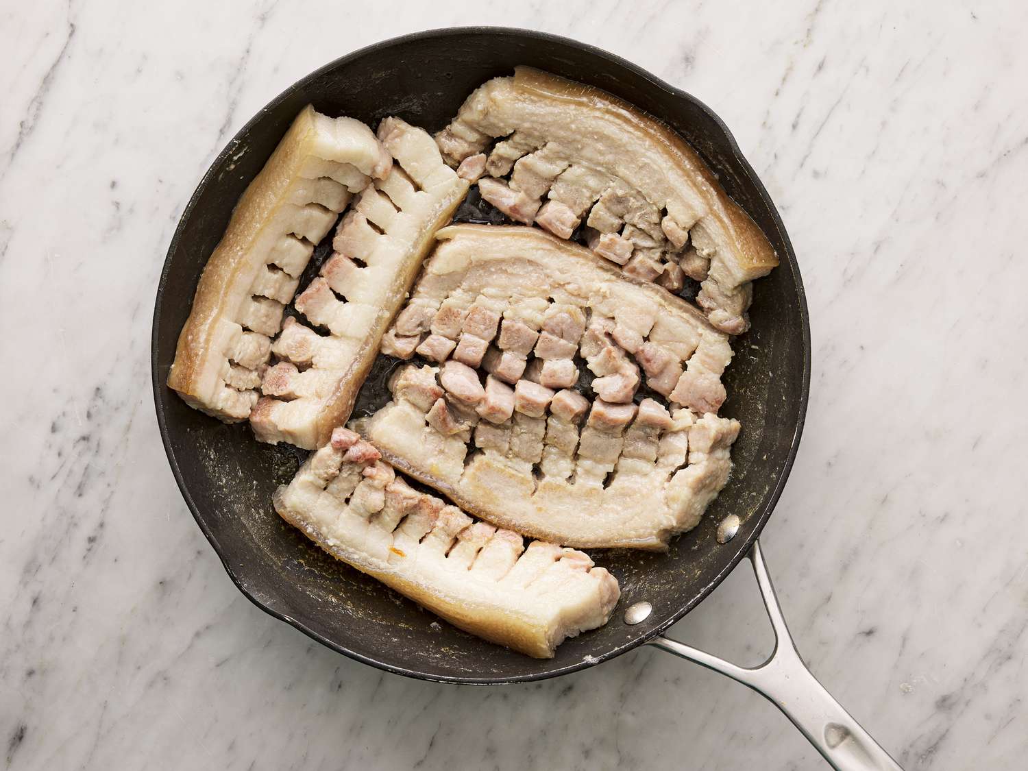 Overhead view of cut pork belly resting in a pan.