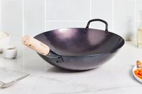 Mammafong Pre-Seasoned Blue Carbon Steel Flat-Bottom Pow Wok displayed on a marble counter next to bowls of ingredients
