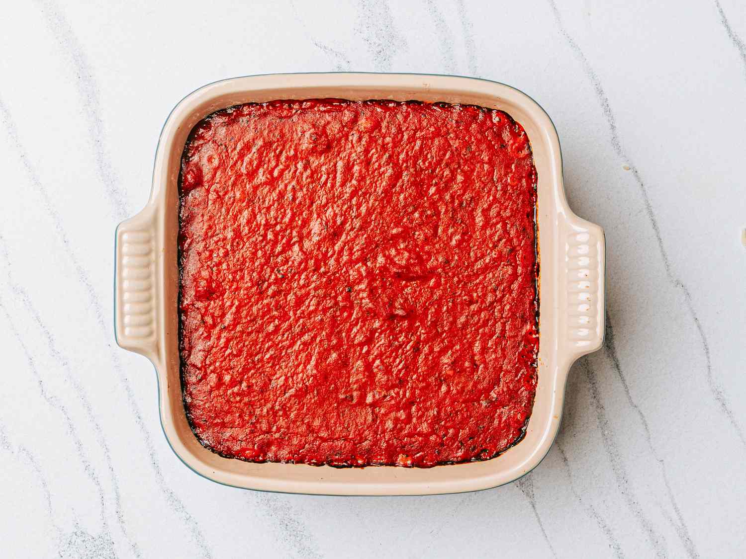 A square baking dish filled with marinara sauce