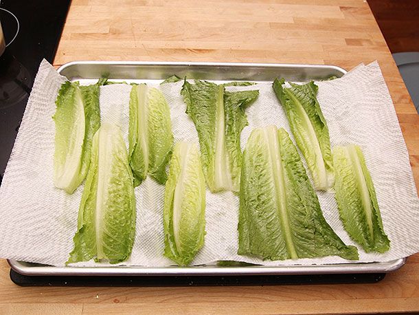 Inner, crisp romaine lettuce leaves lined up on a paper towel–lined sheet tray for Caesar salad.