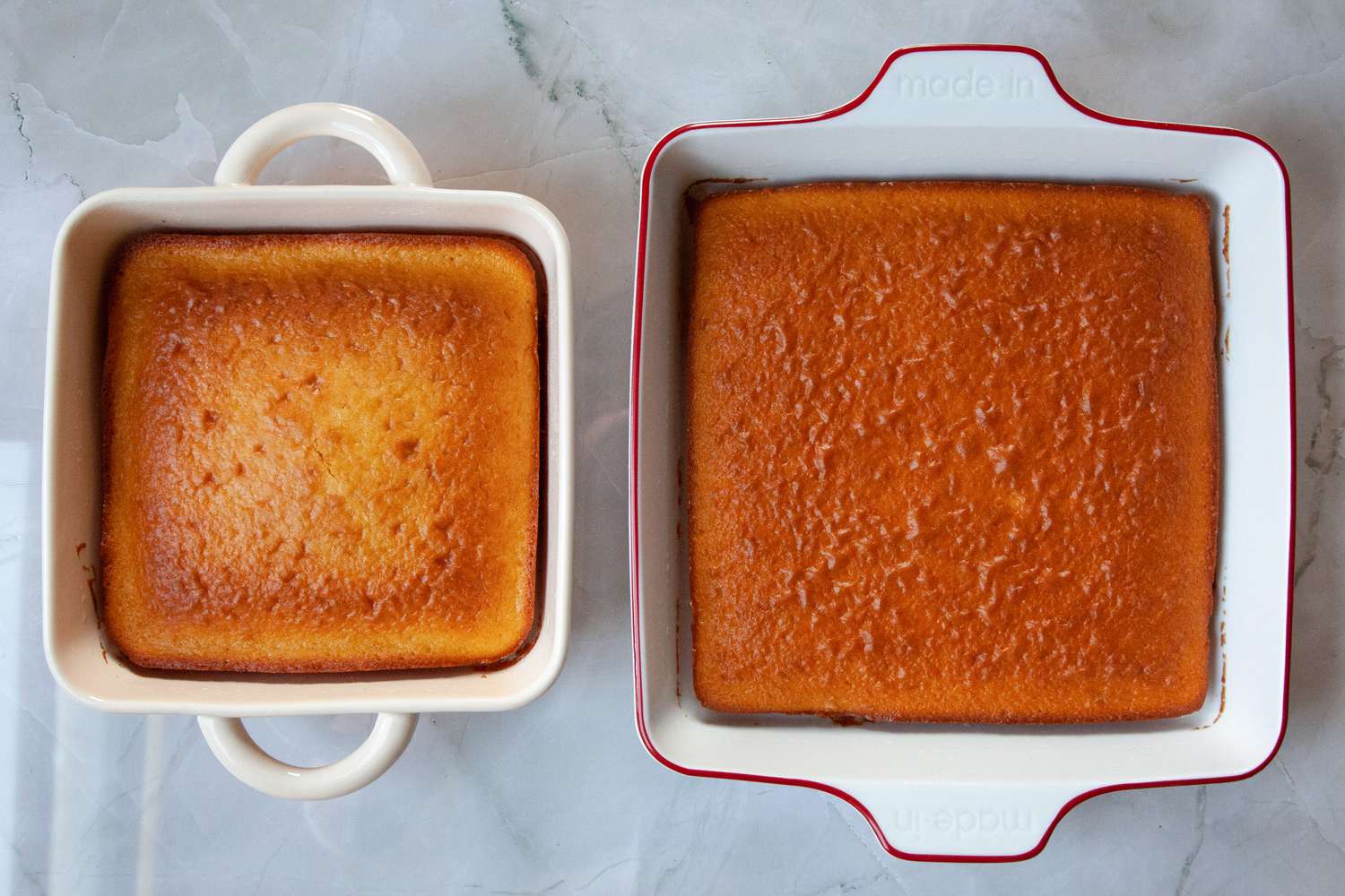 Two ceramic baking pans with baked cakes in them.