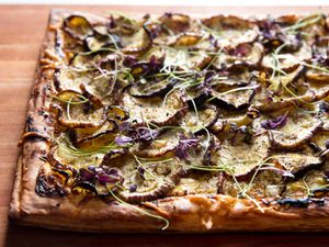 Closeup of an eggplant tart with goat cheese, honey, and nigella seeds.