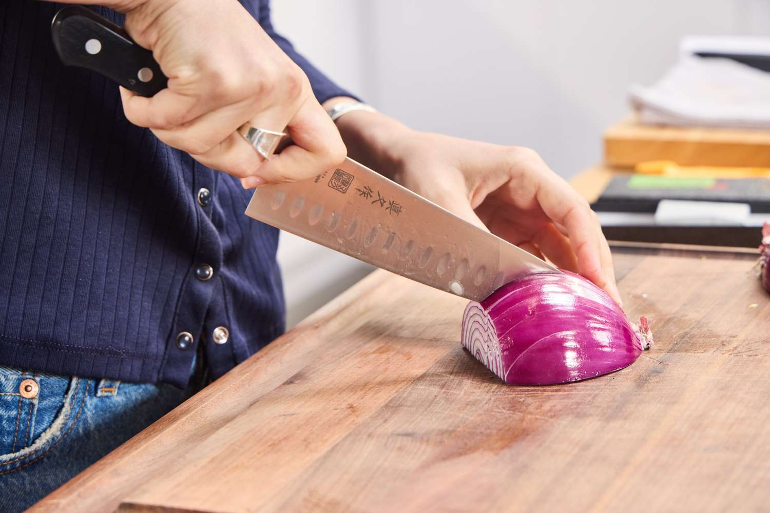 A person slices a red onion using the MAC Professional 8 Inch Hollow Edge Chef's Knife