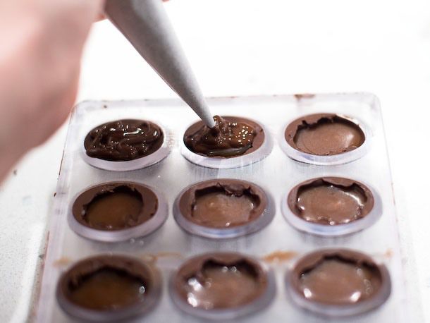 Piping chocolate to the top of the bonbon shells.