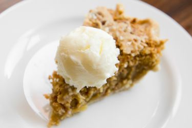 A scoop of ricotta gelato perched atop a slice of pie.