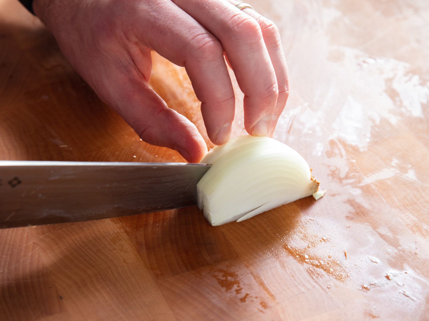 Making first set of vertical cuts along Y-axis of onion quarter.