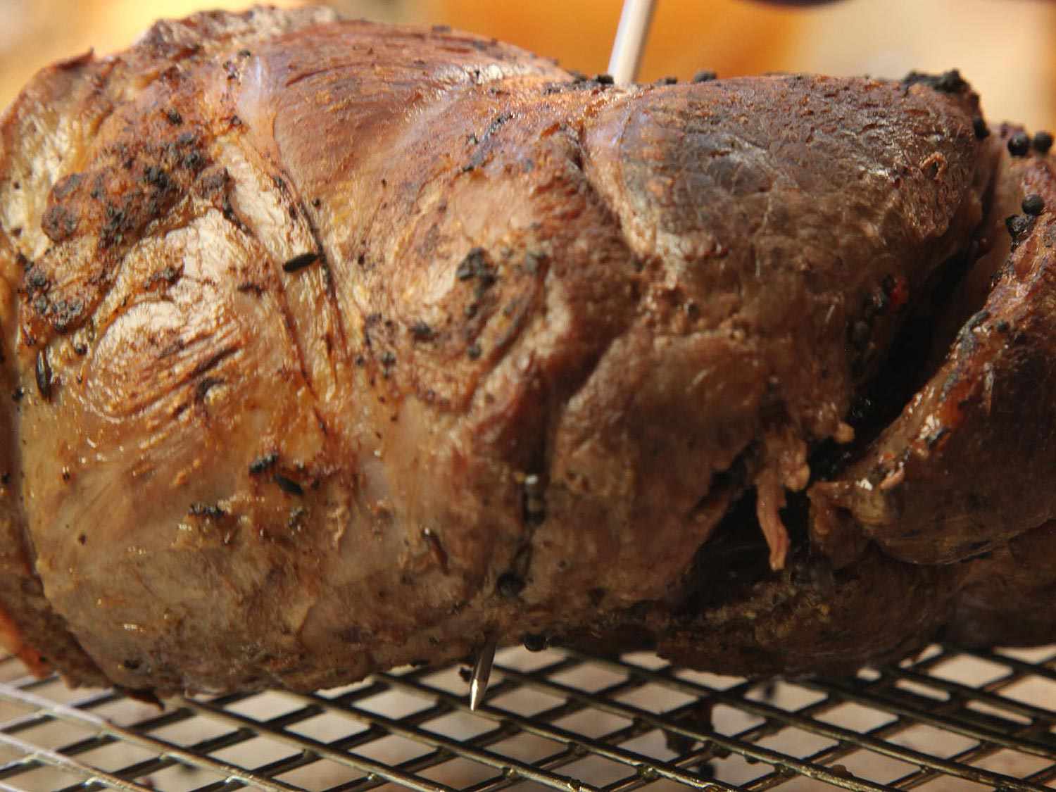 Closeup of a roast with the probe of an instant-read thermometer protruding from the opposite side.