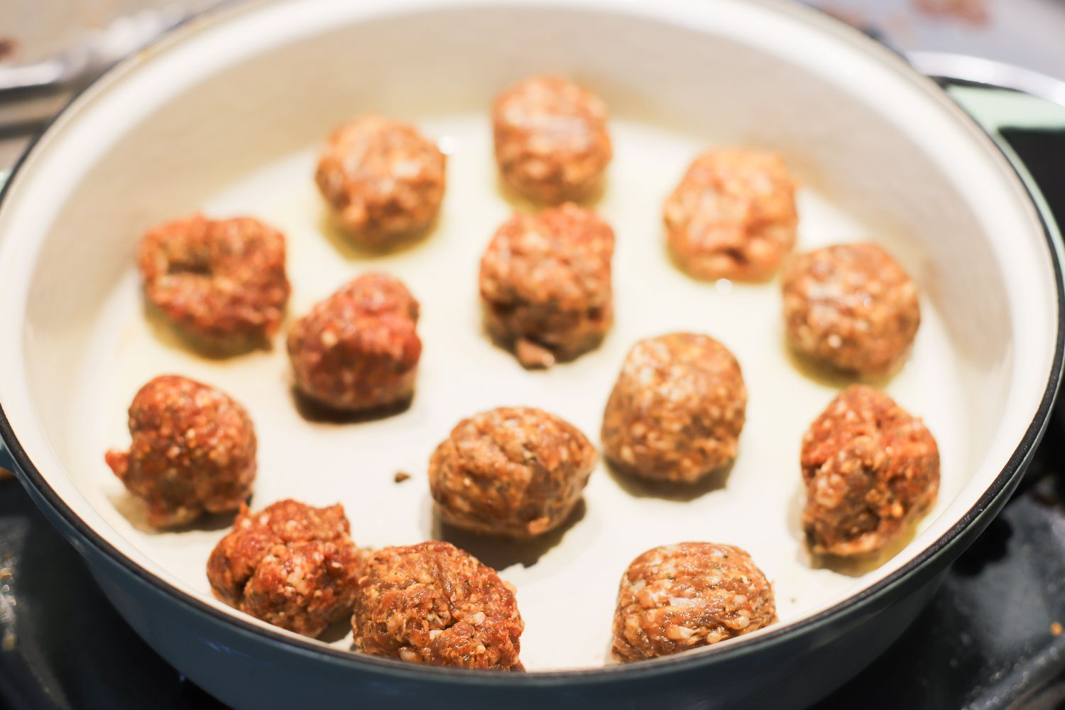 An enameled cast iron braiser with meatballs in it