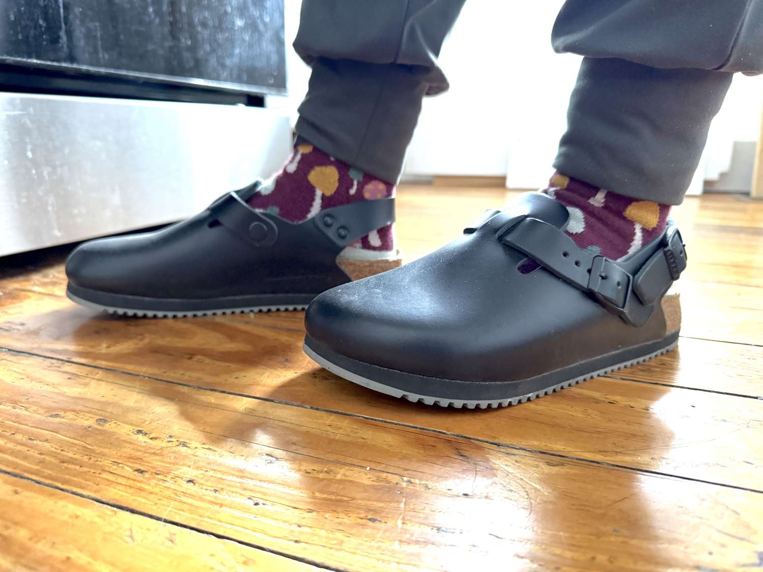A person wearing closed toe kitchen clogs and standing in a kitchen.