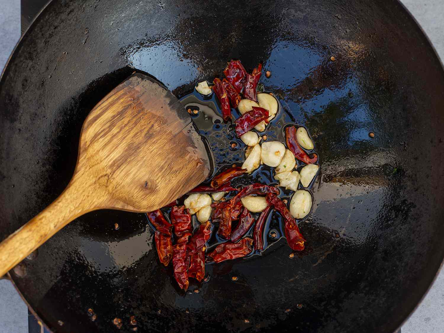 Aromatics being stir-fried in a wok before the addition of deep-fried lamb toothpicks