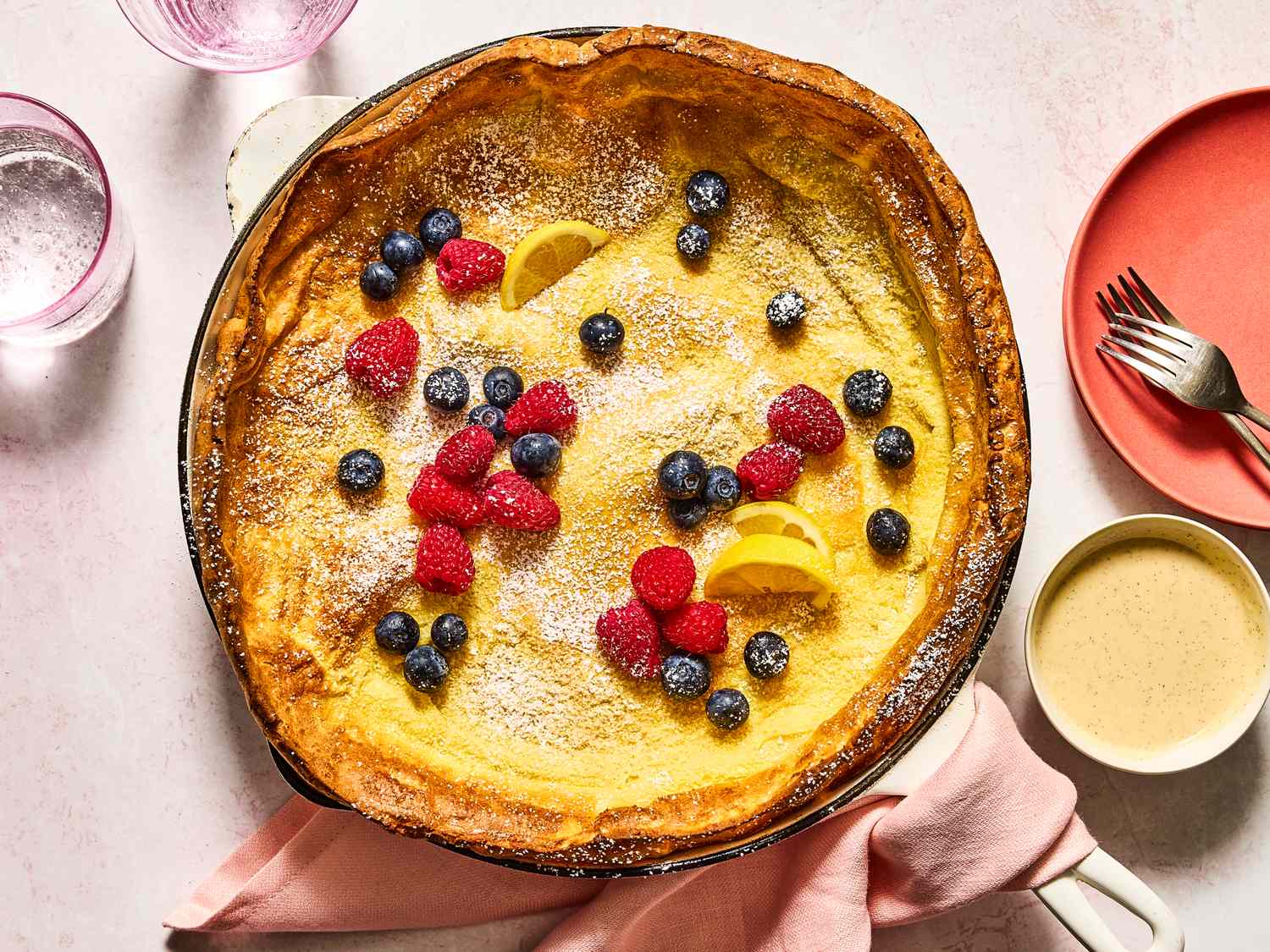 A baked Dutch baby pancake with berries and lemon slices on top