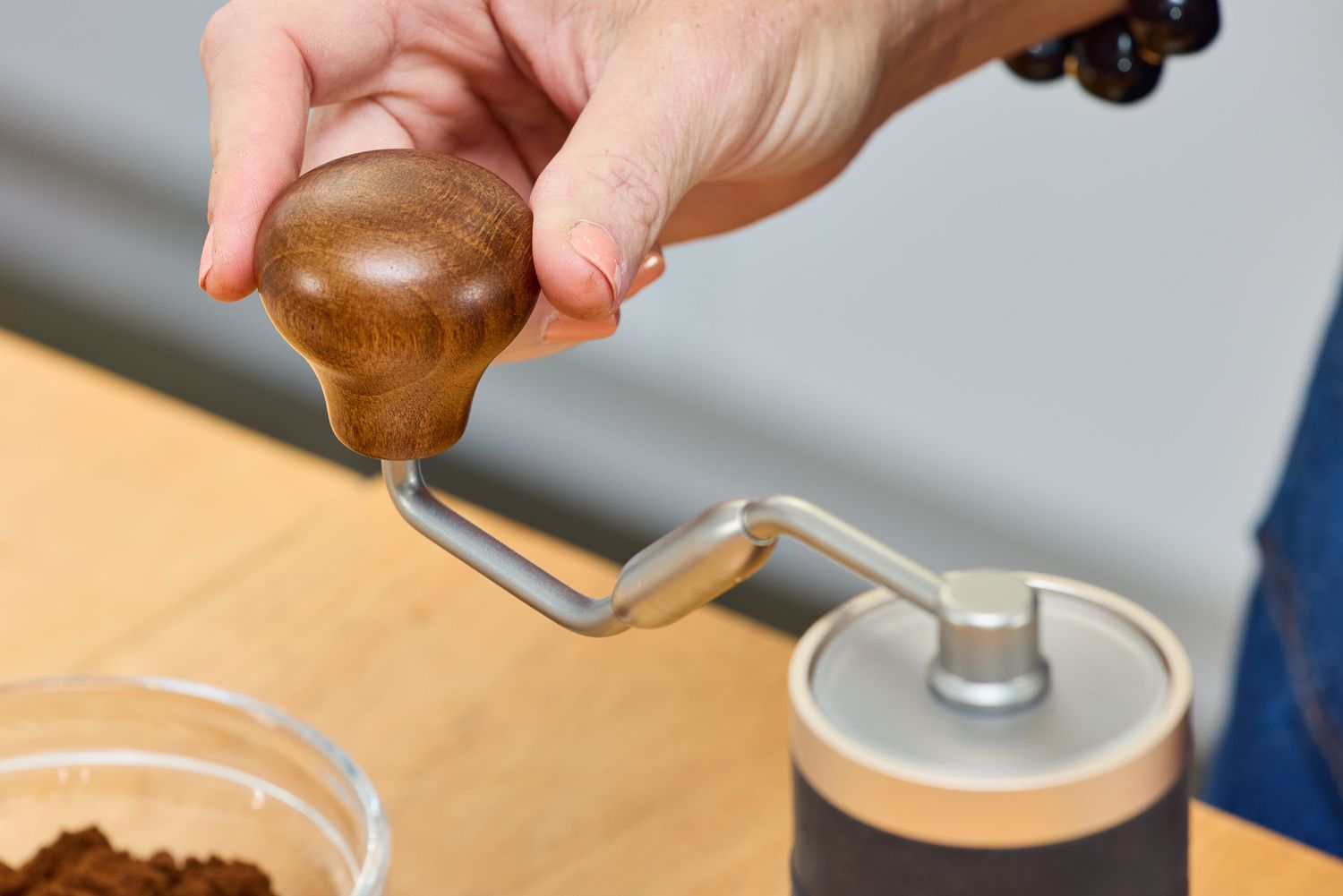 A person turns a crank on the top of the 1Zpresso J Manual Coffee Grinder