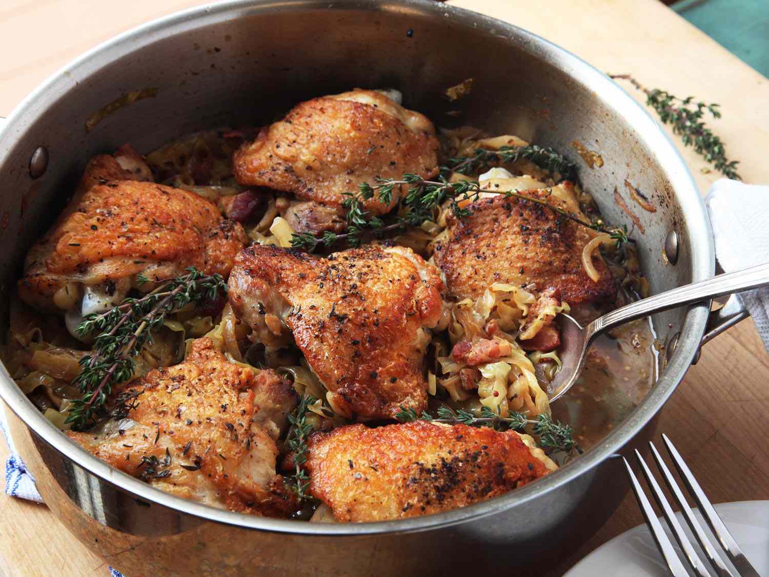 braised chicken thighs in a stainless steel saute pan