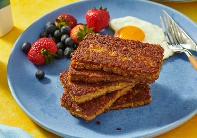 stack of goetta, berries and fried egg on a blue plate. coffee and plate of goetta in the background