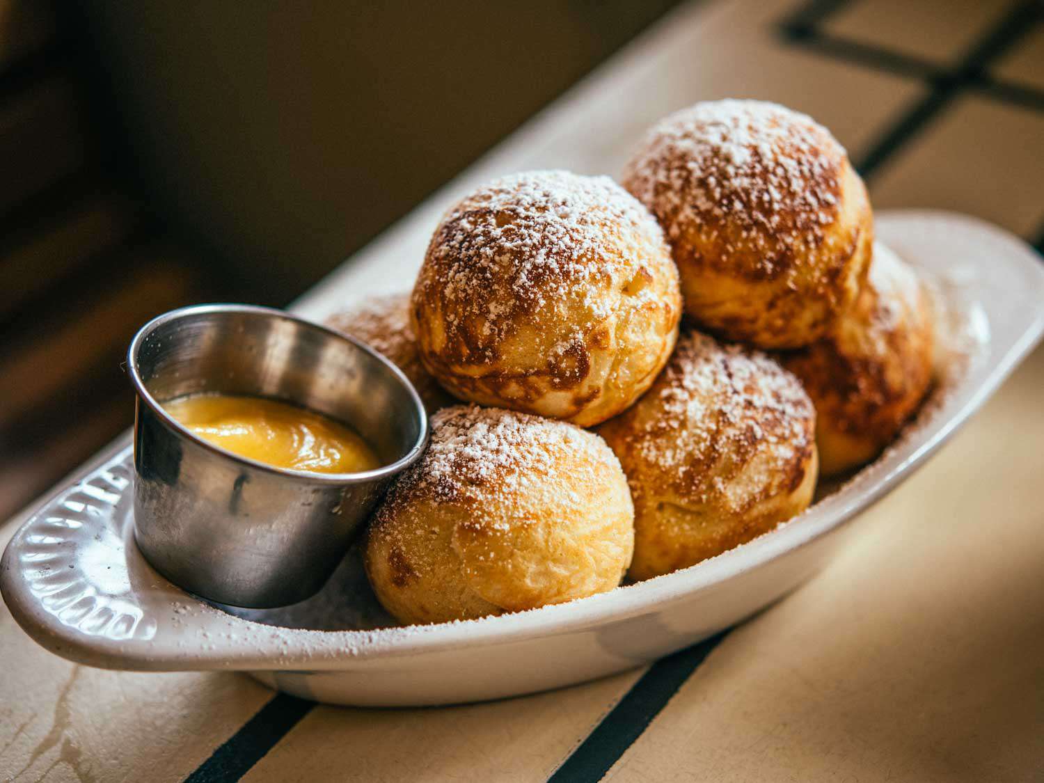 A dish of aebelskivers with dipping sauce at Toast on a white, oval dish.
