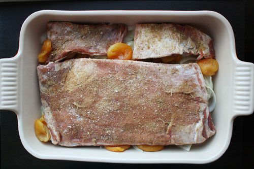 Lamb ribs nestle in a baking dish, filled with dried apricot and onion. 