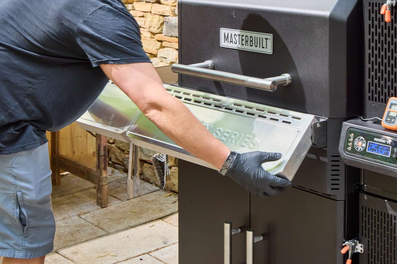 A person extends the shelf on the Masterbuilt Gravity Series 1150 Digital Charcoal Grill and Smoker