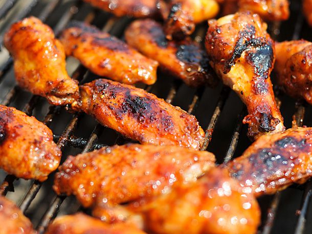 Crisped, partially blackened chicken wings on a grill.