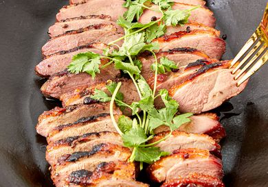 Sliced smoked duck breasts garnished with fresh herbs