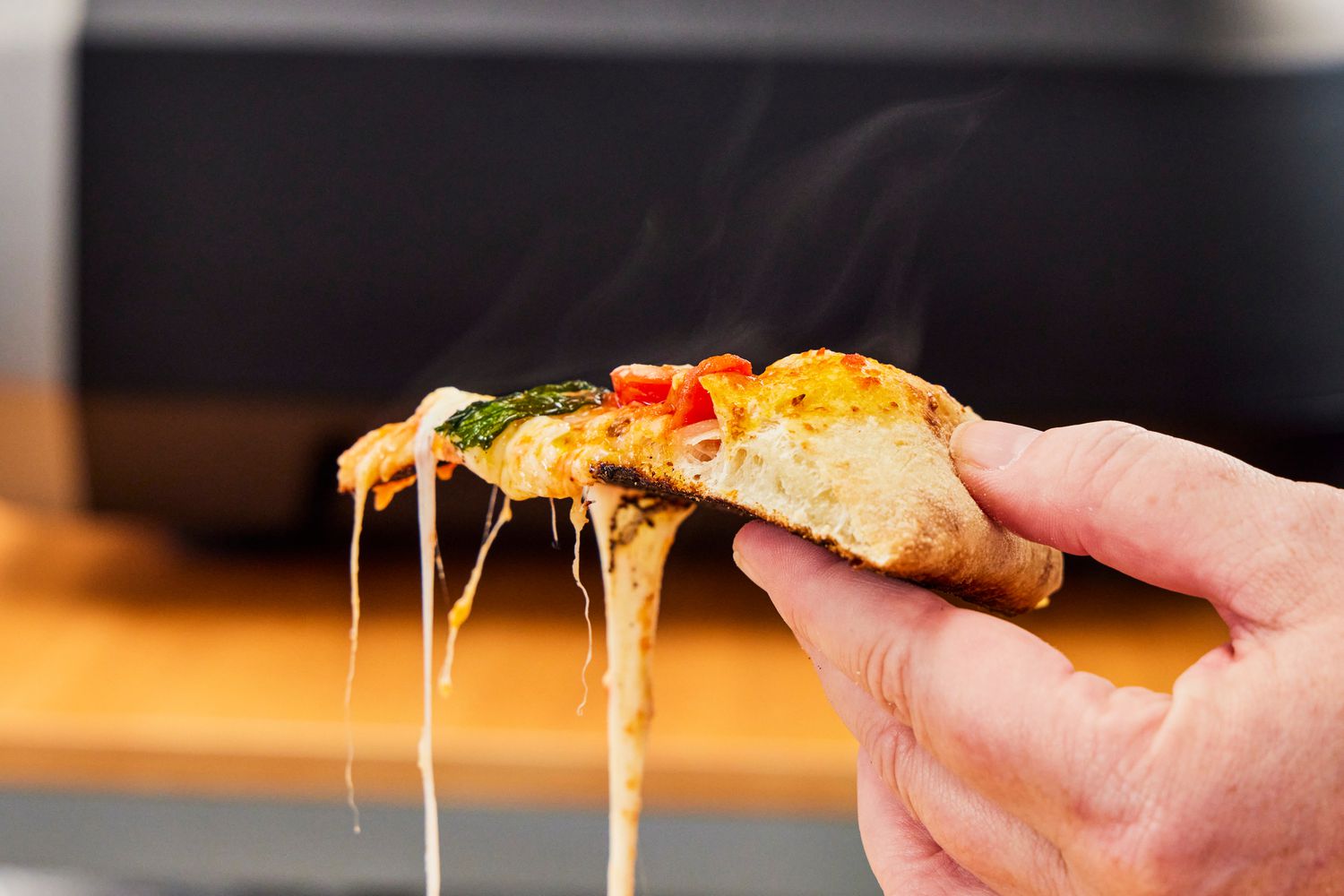 A hand holding a slice of pizza