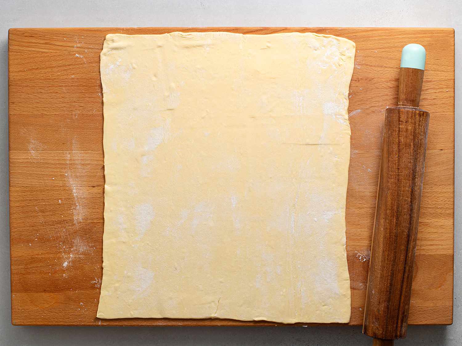 Puff pastry rolled out on a wooden cutting board.