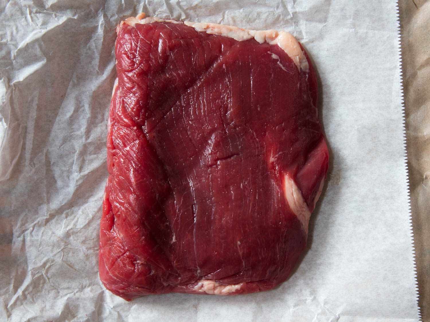 Raw flank steak on its paper wrapping.