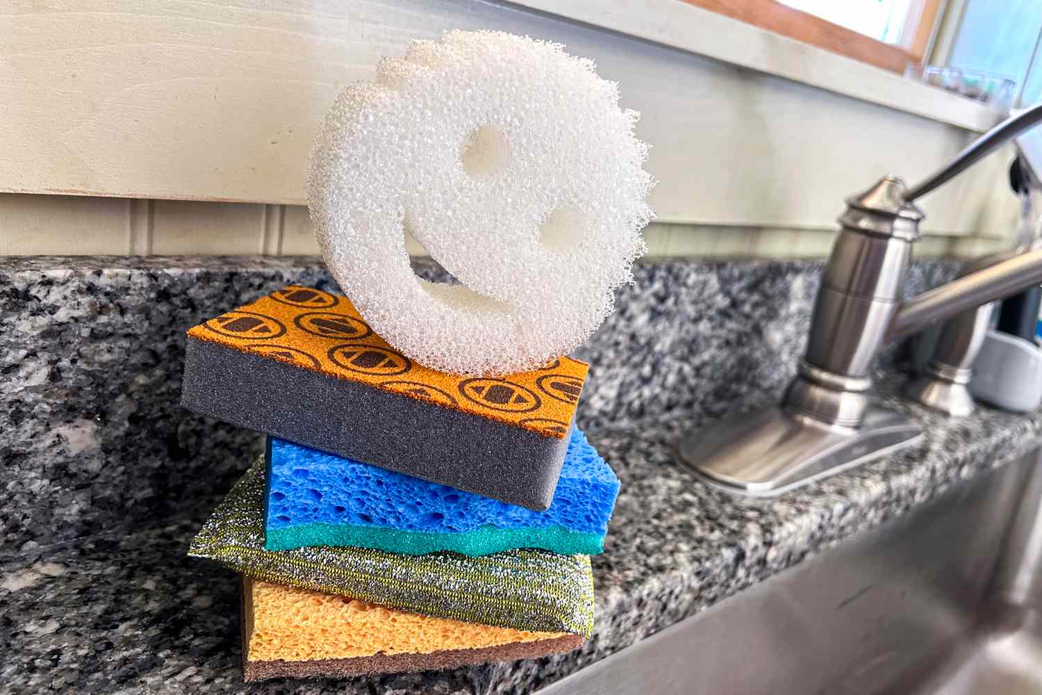 A stack of dishwashing sponges next to a kitchen sink.