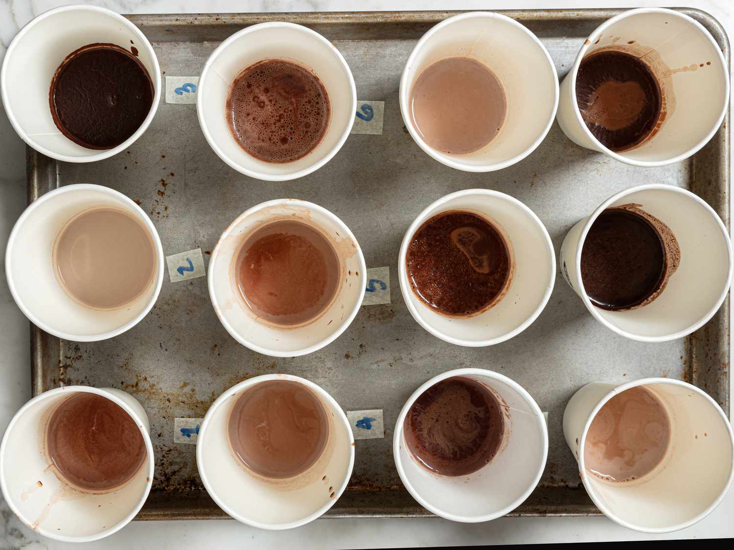 Rows of many different types of hot chocolate in small cups lined up with numbers next to them 