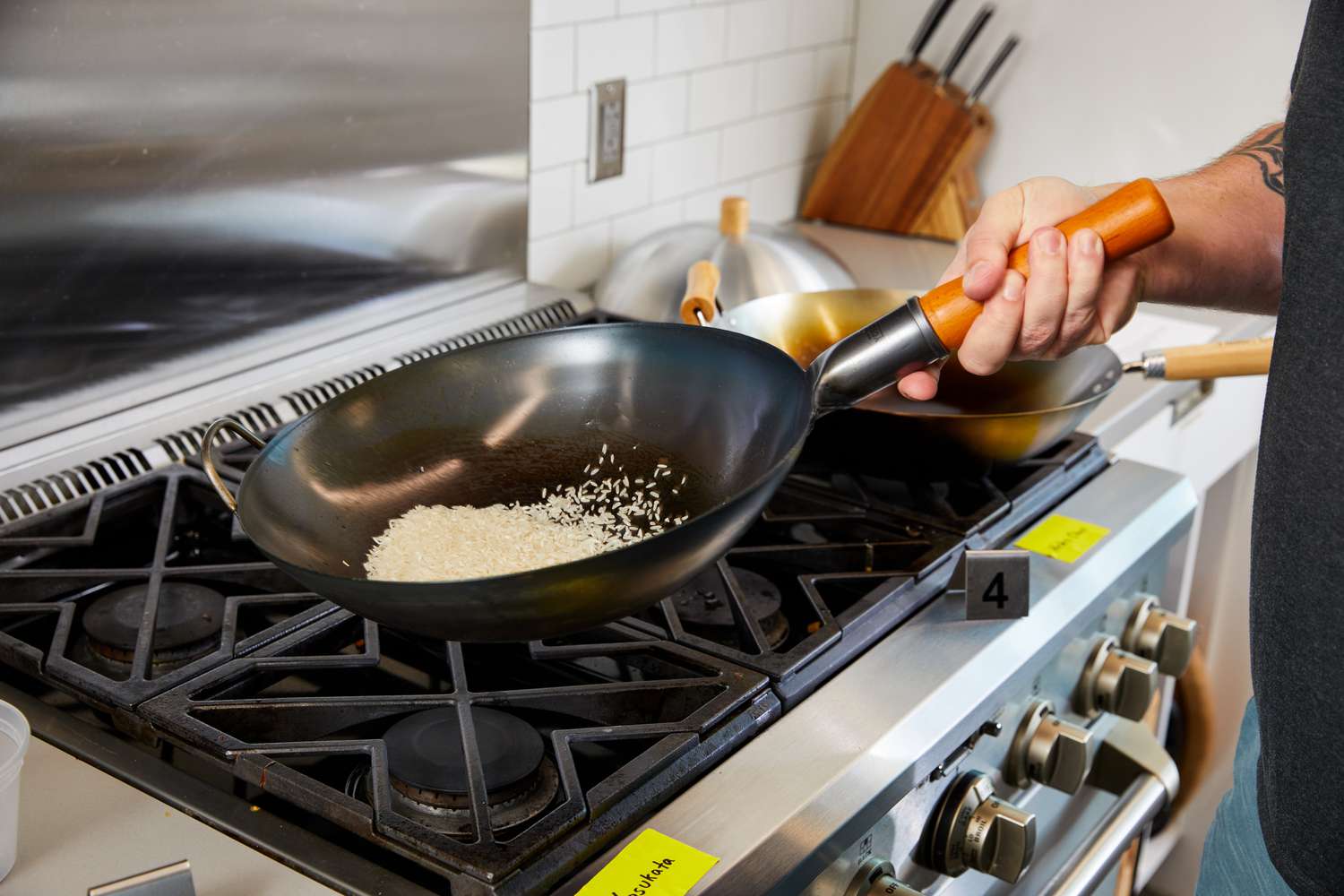 Hand holding the Yosukata Carbon Steel Wok Pan over a gas stove 