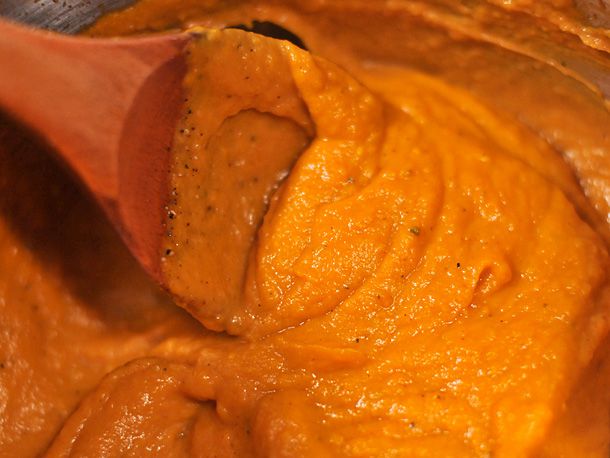 A spoon swirling through butternut squash and sage cream sauce. 