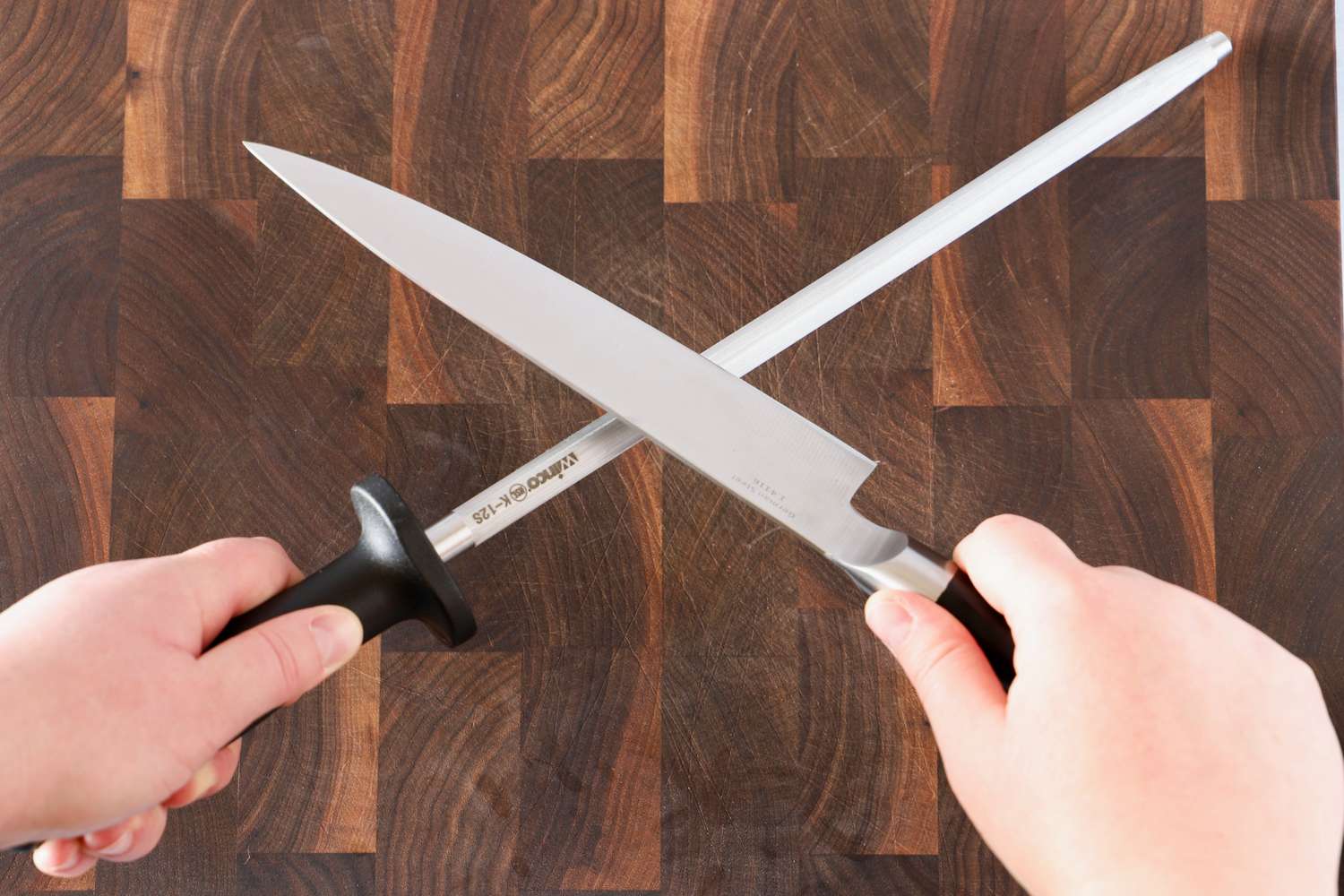 Hands holding a knife and Winco Winware sharpening rod, showing the act of knife sharpening